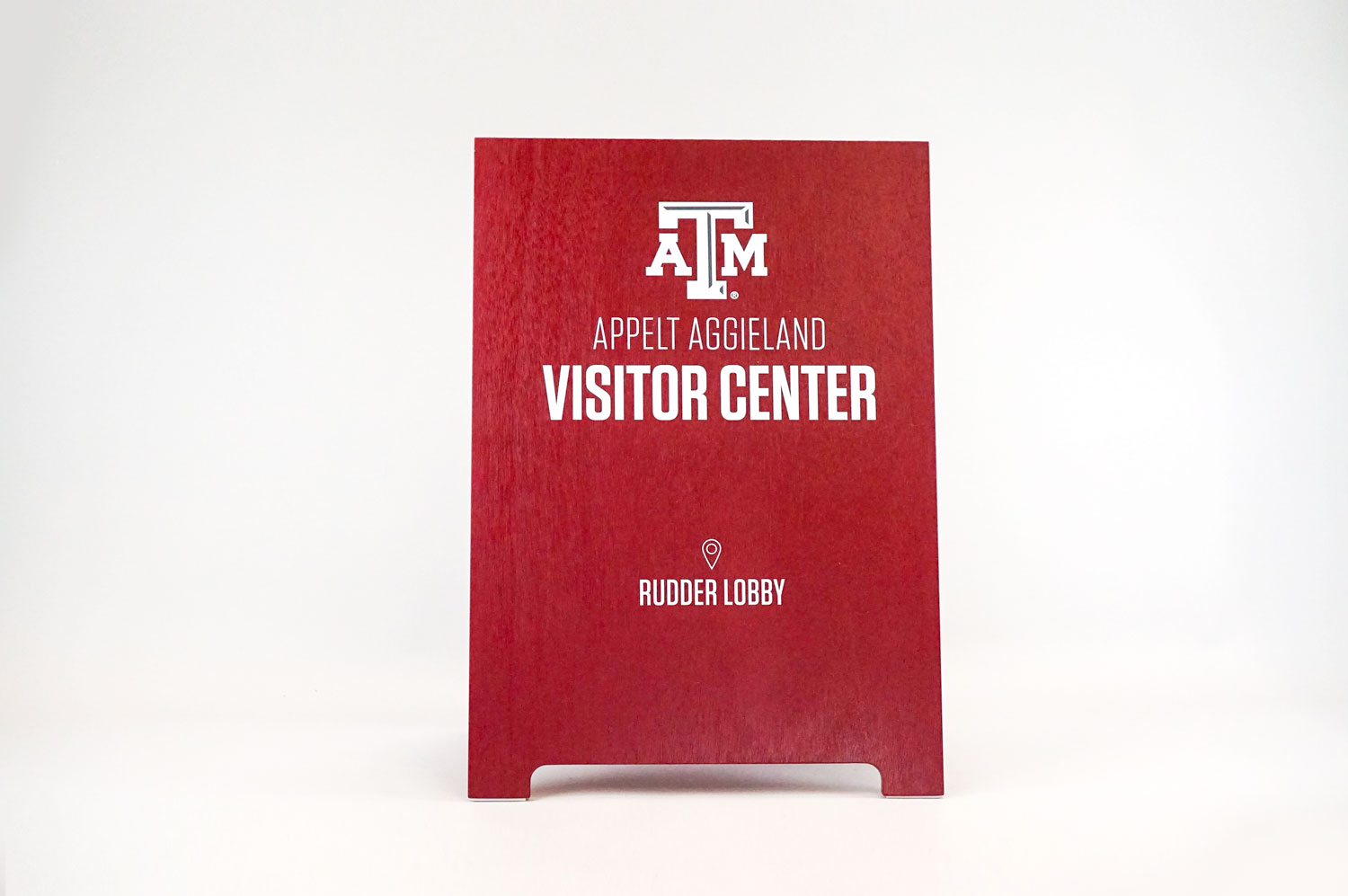 Red A-frame sign with white text for the visitor center at Texas A&M, a public research university in College Station, Texas.