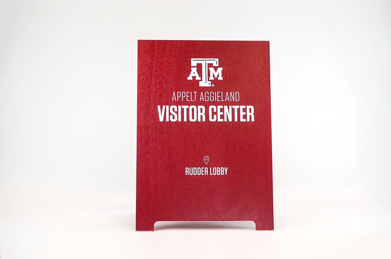 Red A-frame sign with white text for the visitor center at Texas A&M, a public research university in College Station, Texas. Red A-frame sign with white text for the visitor center at Texas A&M, a public research university in College Station, Texas.