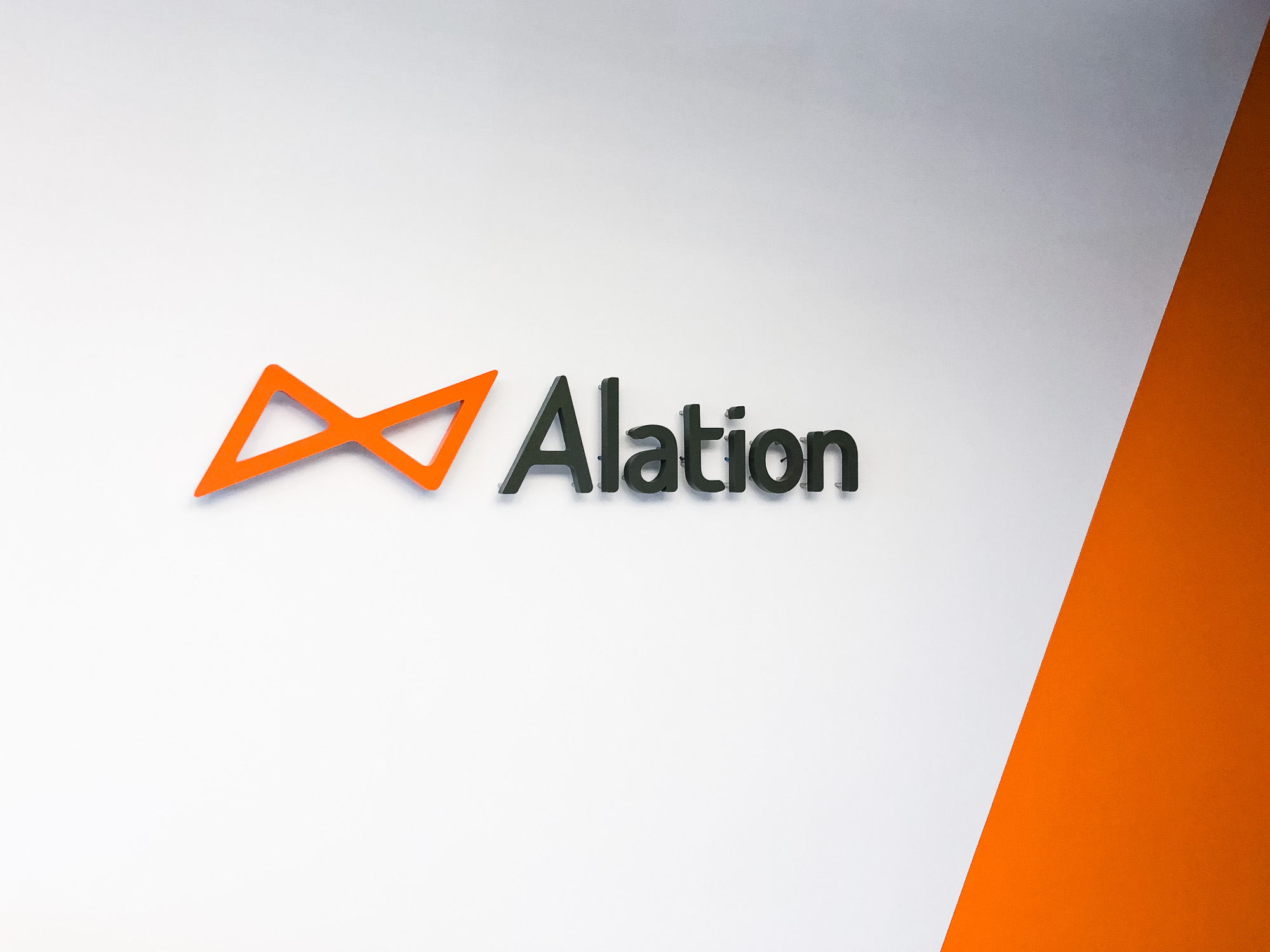 Illuminated black and orange lobby sign on color blocked wall for Alation, a data catalog company based in Redwood City, CA Illuminated black and orange lobby sign on color blocked wall for Alation, a data catalog company based in Redwood City, CA