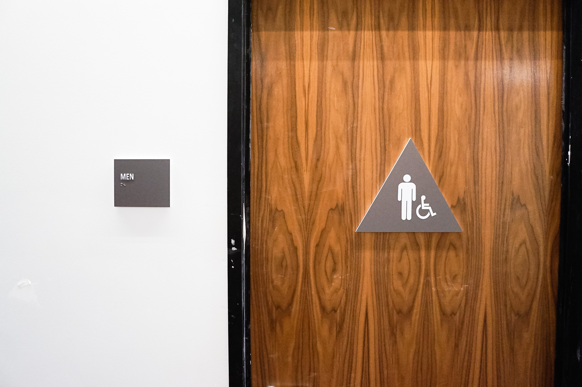 Minimal grey and white CA ADA restroom signs for Baker McKenzie, a multinational law firm.