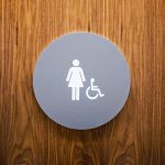 Minimal grey and white CA ADA restroom signs for Baker McKenzie, a multinational law firm.