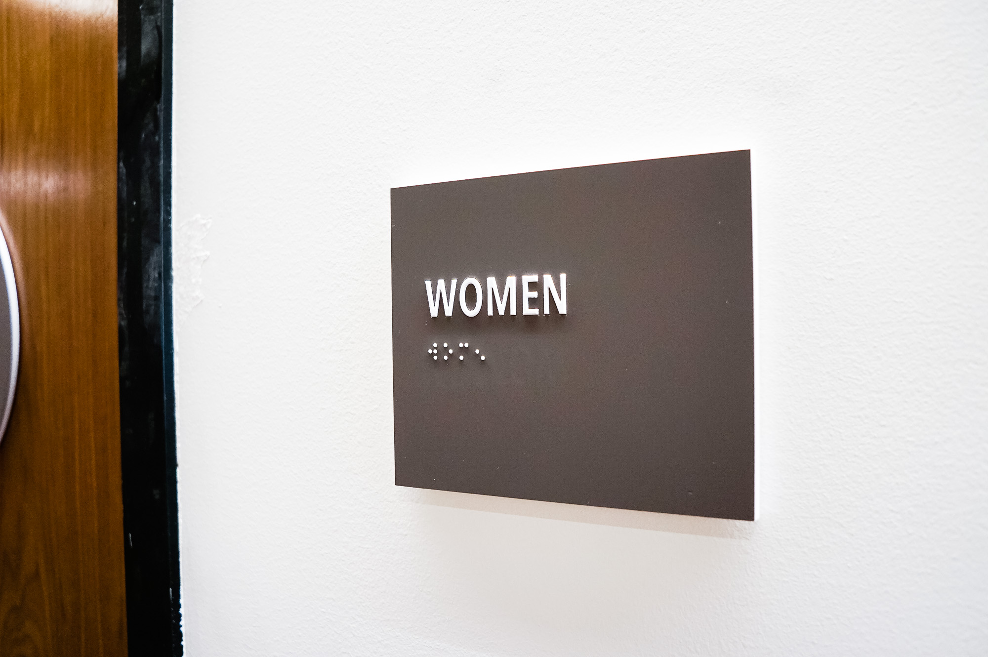 Minimal grey and white CA ADA restroom signs for Baker McKenzie, a multinational law firm.
