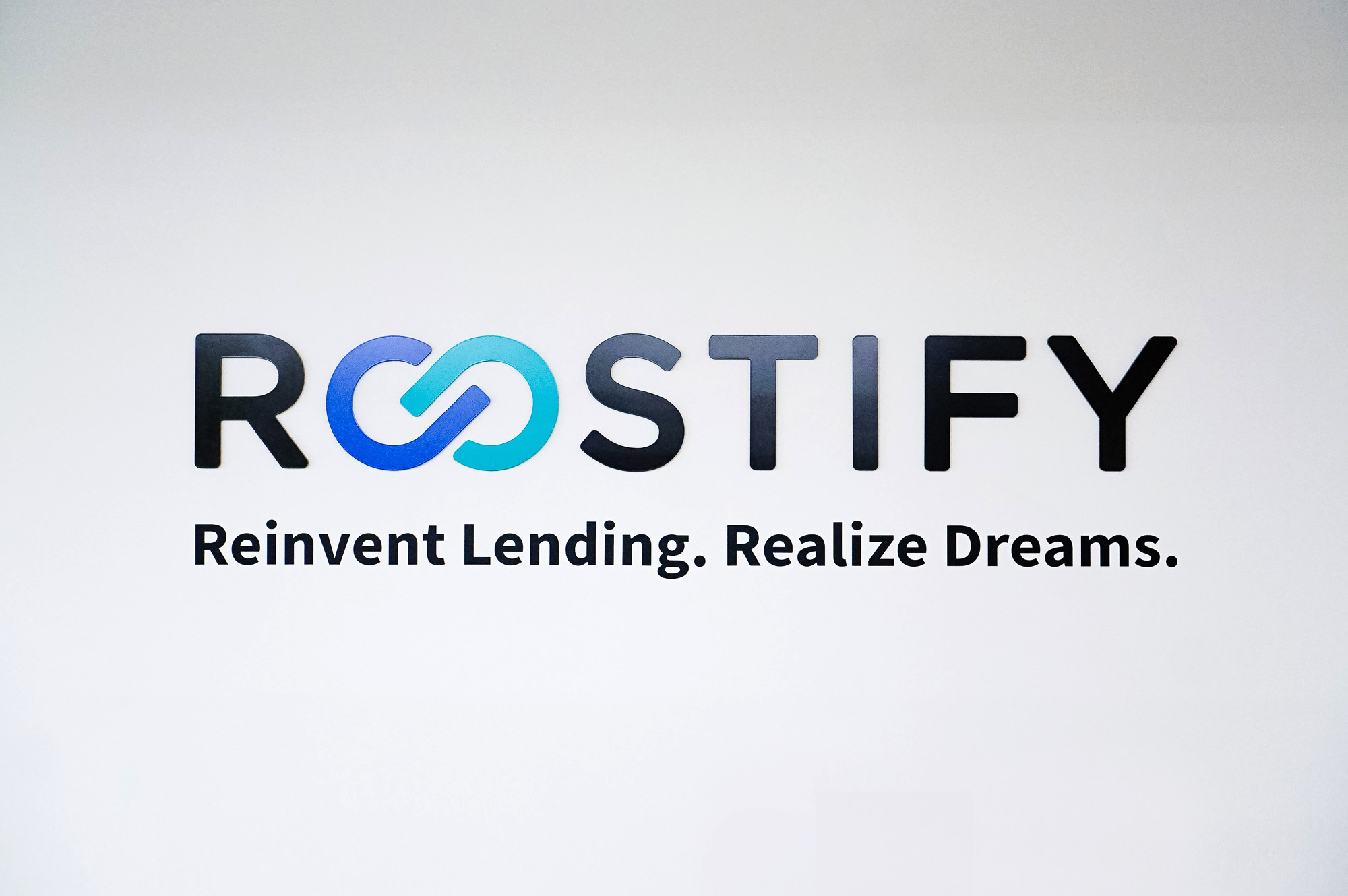 Dimensional, full color logo on white wall in lobby and elevator vestibule for the San Francisco office of Roostify, an integrated digital mortgage software platform.