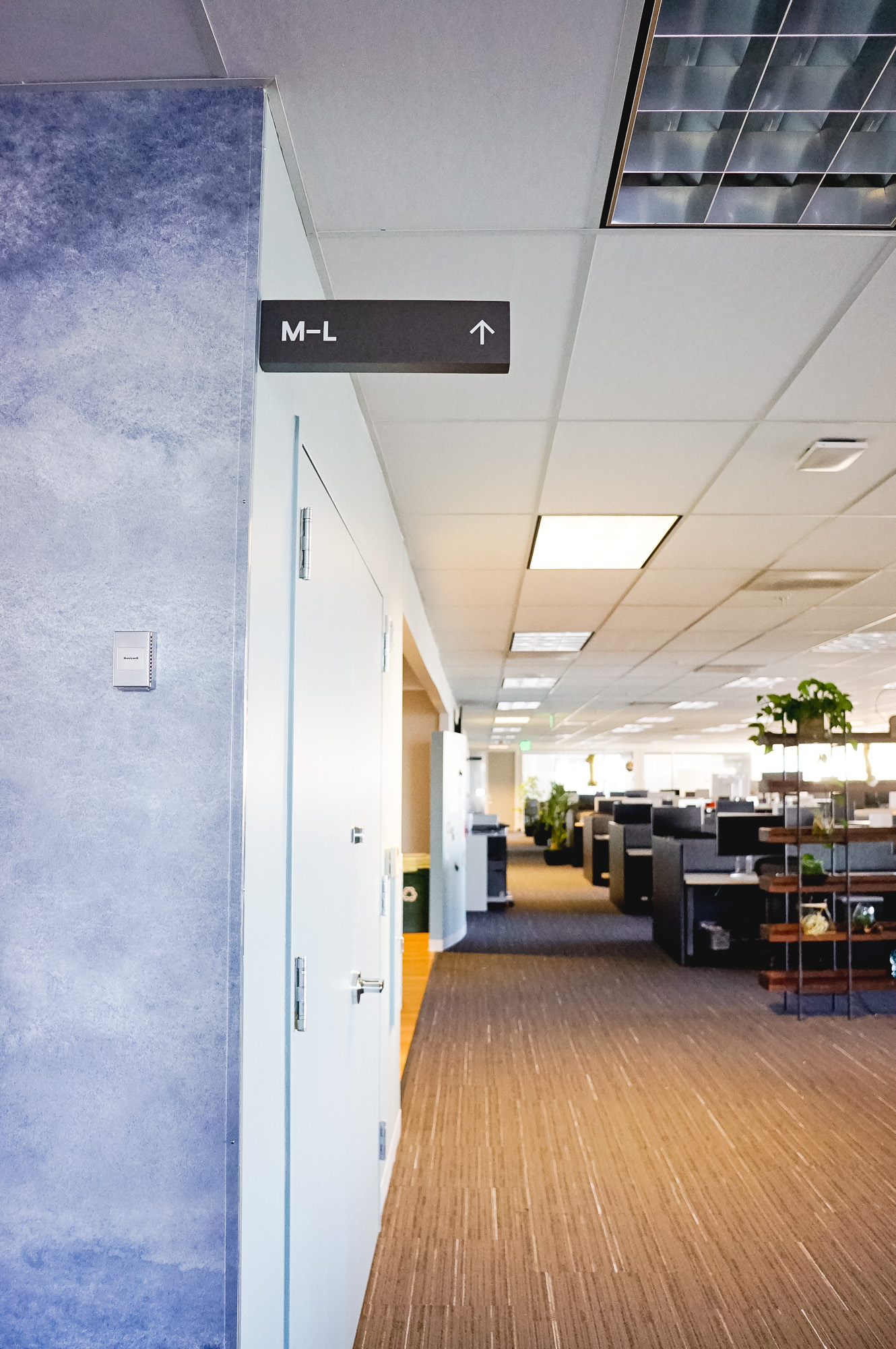 Overhead dark grey wayfinding sign with white text for a San Francisco office of Slack, an American cloud-based set of proprietary team collaboration tools and services.