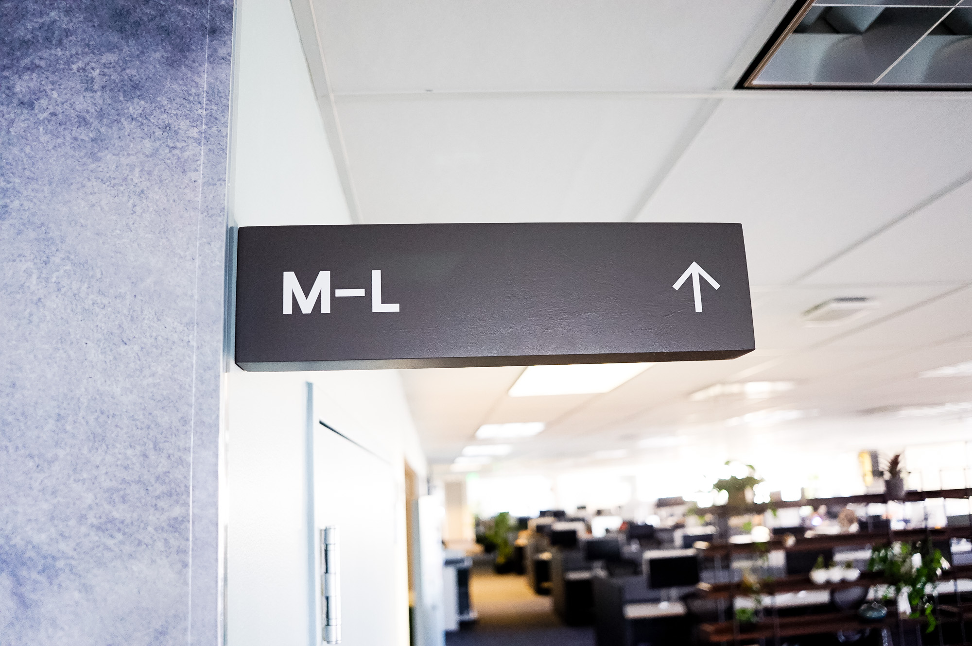 Overhead dark grey wayfinding sign with white text for a San Francisco office of Slack, an American cloud-based set of proprietary team collaboration tools and services. Overhead dark grey wayfinding sign with white text for a San Francisco office of Slack, an American cloud-based set of proprietary team collaboration tools and services.