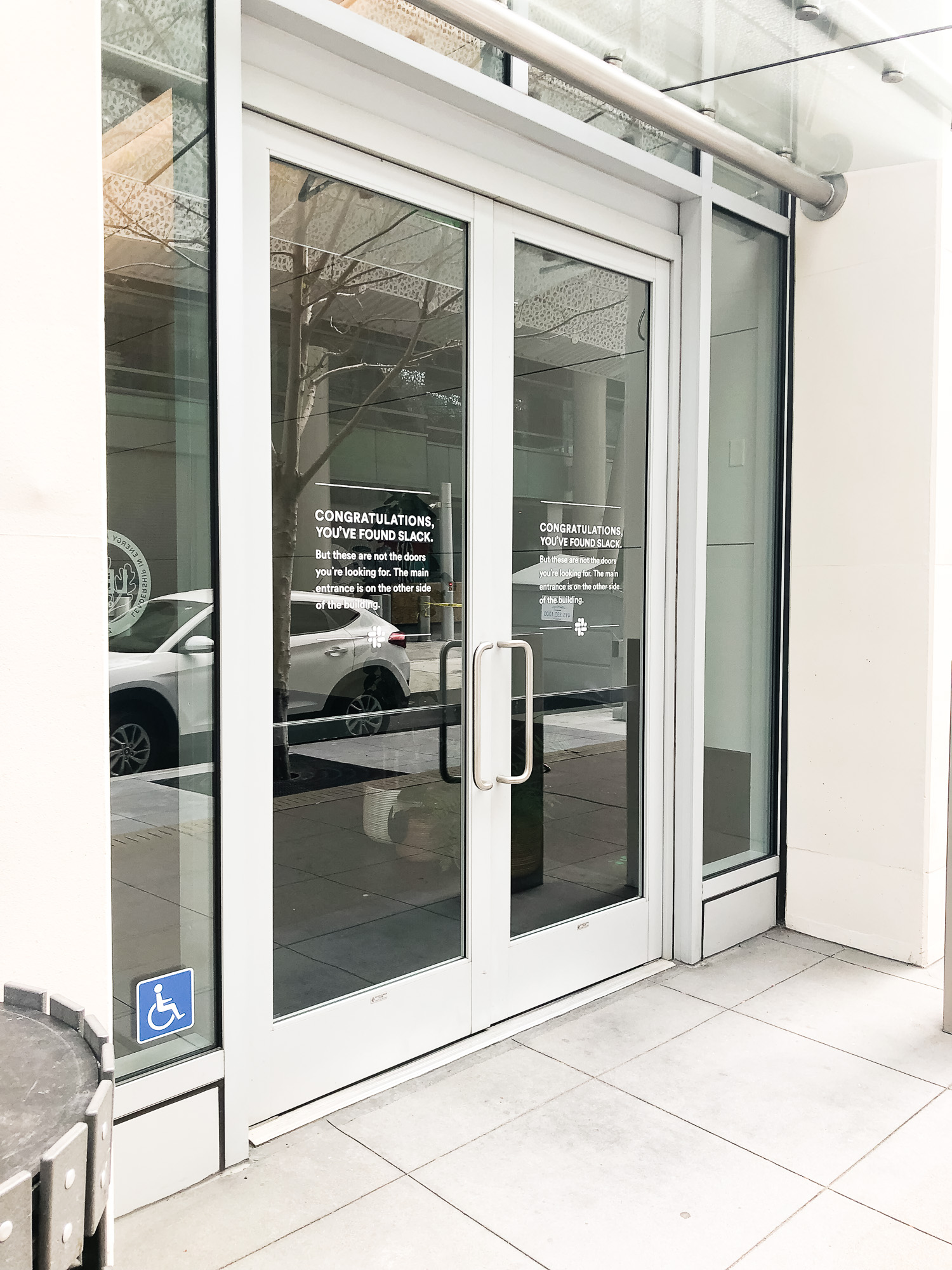 Matte white vinyl wayfinding sign with white text on glass doors for the San Francisco office of Slack, an American cloud-based set of proprietary team collaboration tools and services. Matte white vinyl wayfinding sign with white text on glass doors for the San Francisco office of Slack, an American cloud-based set of proprietary team collaboration tools and services.