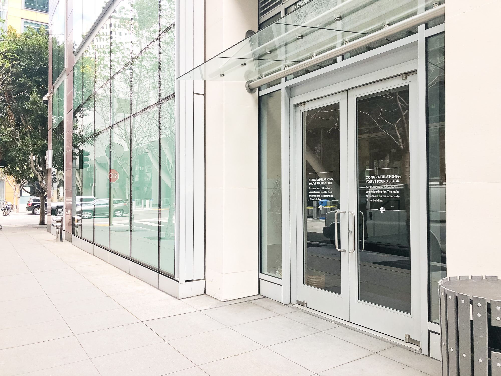 Matte white vinyl wayfinding sign with white text on glass doors for the San Francisco office of Slack, an American cloud-based set of proprietary team collaboration tools and services. Matte white vinyl wayfinding sign with white text on glass doors for the San Francisco office of Slack, an American cloud-based set of proprietary team collaboration tools and services.