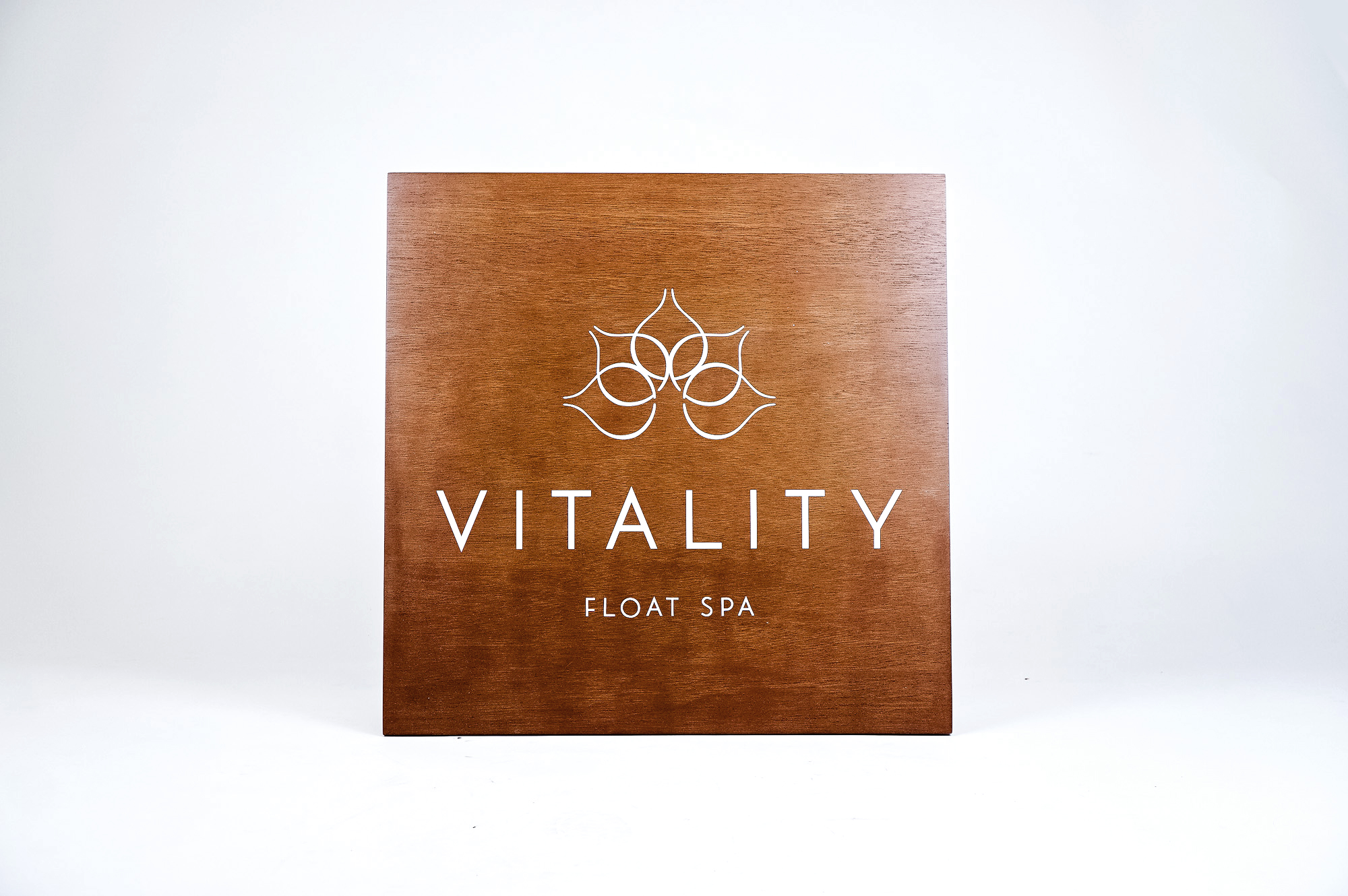 Dark wood retail blade sign with white artwork for Vitality, a massage therapy and wellness studio located in Carytown, Virginia. Dark wood retail blade sign with white artwork for Vitality, a massage therapy and wellness studio located in Carytown, Virginia.