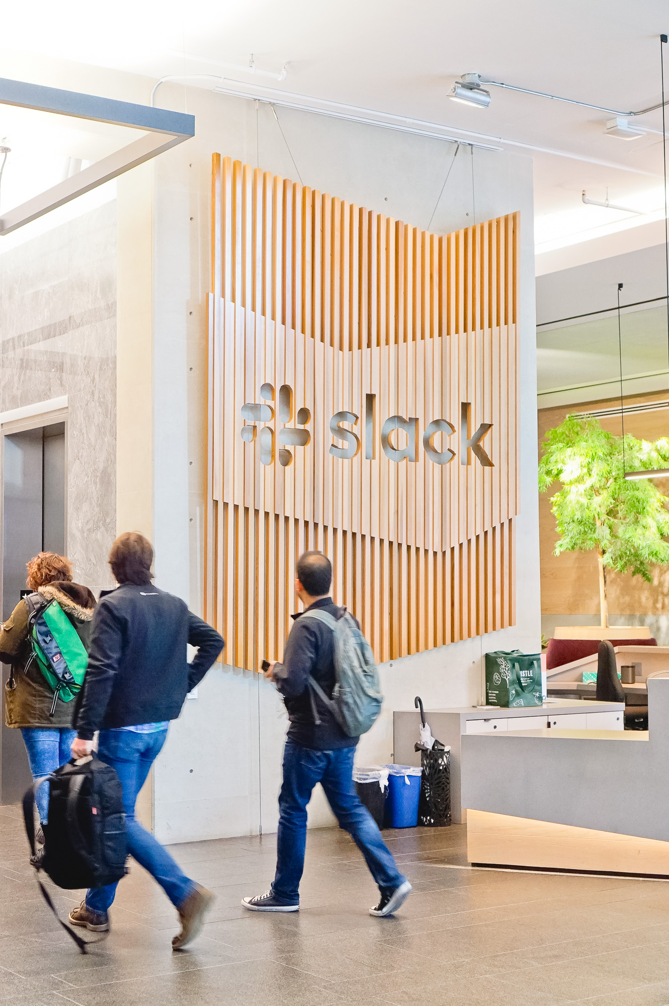 Modern, large-scale slat wood lobby sign on concrete wall at the San Francisco lobby of Slack, an American cloud-based set of team collaboration tools and services. Modern, large-scale slat wood lobby sign on concrete wall at the San Francisco lobby of Slack, an American cloud-based set of team collaboration tools and services.