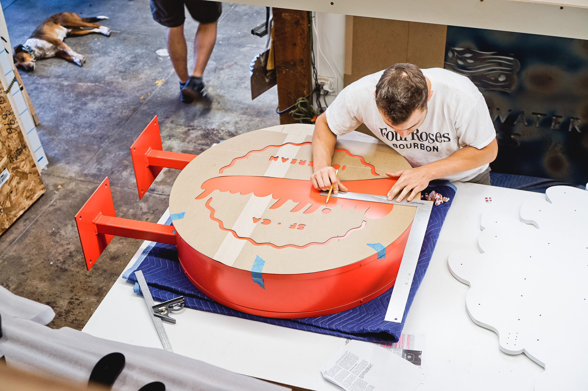 Red circular blade sign with white script for Milkbomb, a sweet stop for donut ice cream sandwiches.