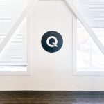 Black and white circular sign on white wall for the office of Qordoba, a content AI technology to help organizations achieve consistency and clarity across all types of content.