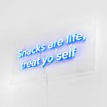 Blue neon style "Snacks are life, treat yo self" sign on clear acrylic backer board with exposed wiring for the kitchen pantry at Zumper, a full-service rental platform.