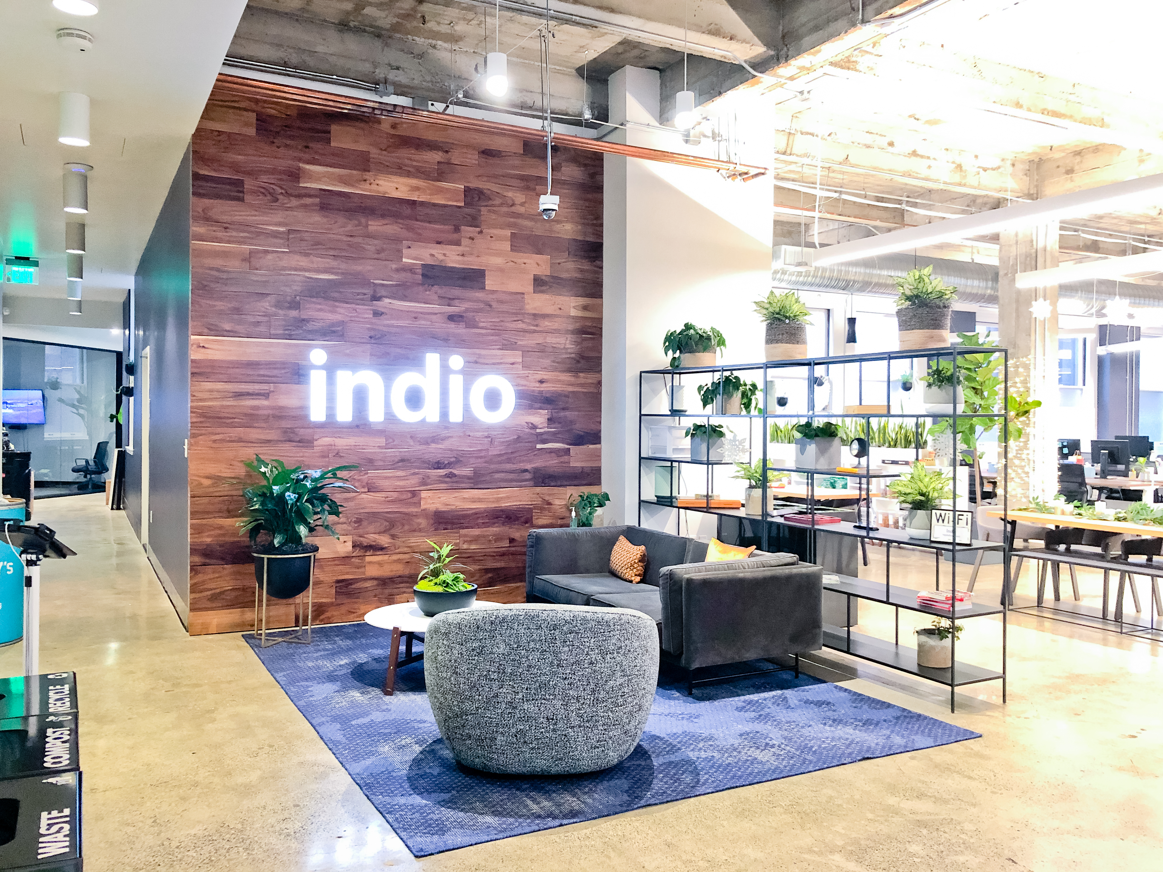 Full wall installation with dark wood and an illuminated, built-in logo for the San Francisco lobby of Indio, a company that simplifies the insurance application process for brokers and their clients.