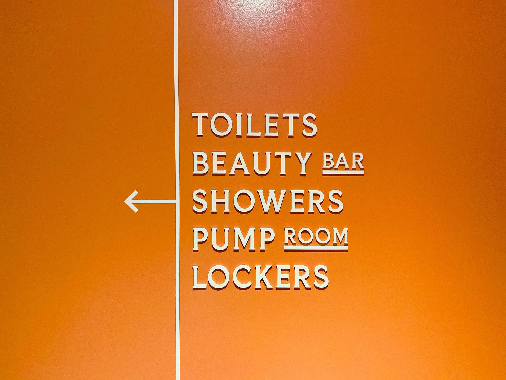 the-wing-wayfinding-straight2 Cream colored, typographic wayfinding sign on orange wall for The Wing, a co-working space in San Francisco.
