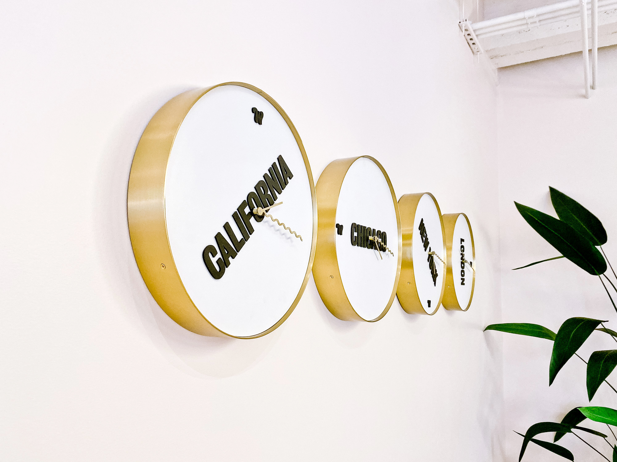 wing-clocks-row Custom brass and white international time zone clock wall for the San Francisco expansion of The Wing, a network of work and community spaces designed for women.