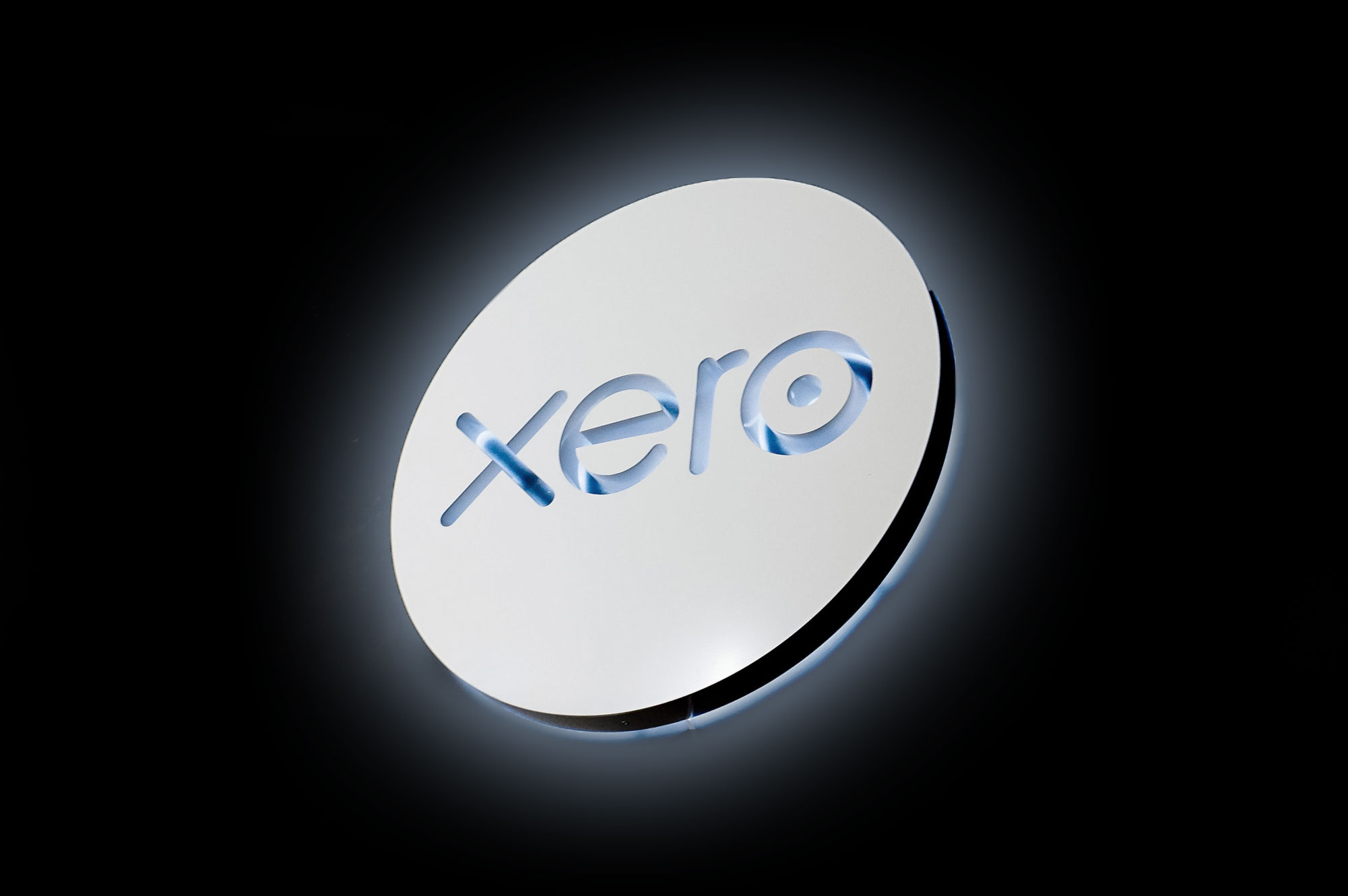 Illuminated, back-lit white sign on blue lobby wall for Xero, a cloud-based accounting software platform for small and medium-sized businesses.