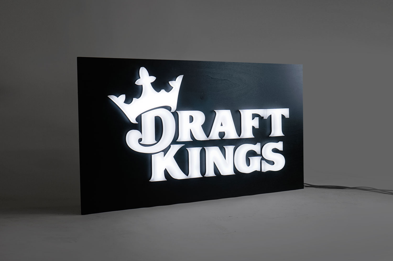 Illuminated, face-lit white logo on a black painted backer/wall for the San Francisco office of Draft Kings, an American daily fantasy sports contest and sports betting provider. Illuminated, face-lit white logo on a black painted backer/wall for the San Francisco office of Draft Kings, an American daily fantasy sports contest and sports betting provider.