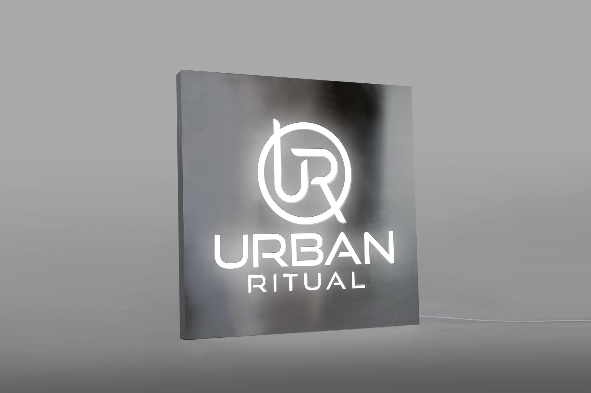 Brushed steel, interior-lit, large square wall sign for Urban Ritual, a fitness studio located in Styles Studios, a boutique fitness studio in Peoria, IL. Brushed steel, interior-lit, large square wall sign for Urban Ritual, a fitness studio located in Styles Studios, a boutique fitness studio in Peoria, IL.