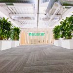 Wood slat dividing wall wiht green logo for lobby/reception desk area at the San Francisco office of Neustar, an American technology company that provides real-time information and analytics.