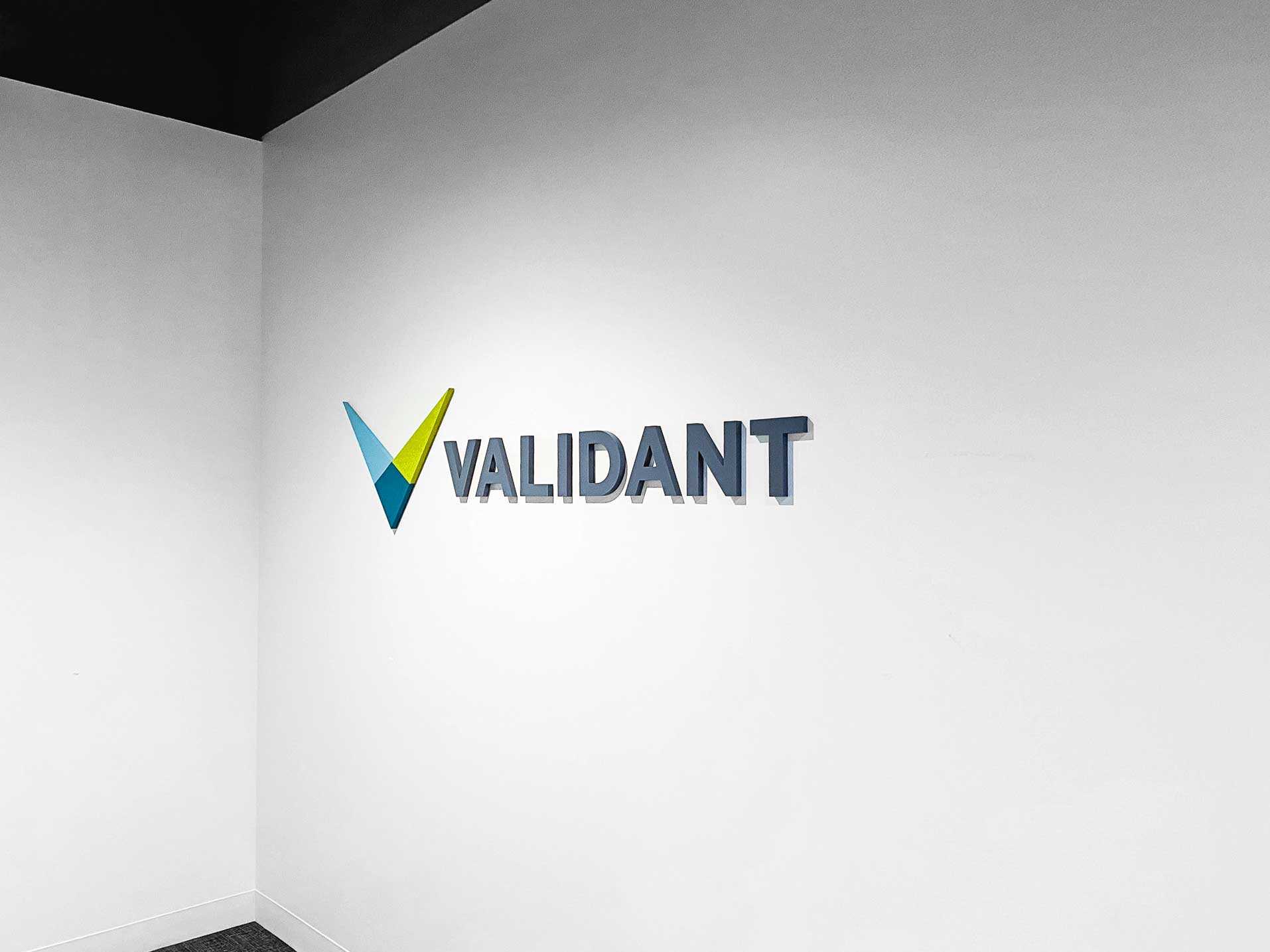 Full color dimensional logo on white wall for the lobby of Validant, a San Francisco based company that delivers end-to-end quality, compliance, and regulatory consulting service for healthcare companies around the world.