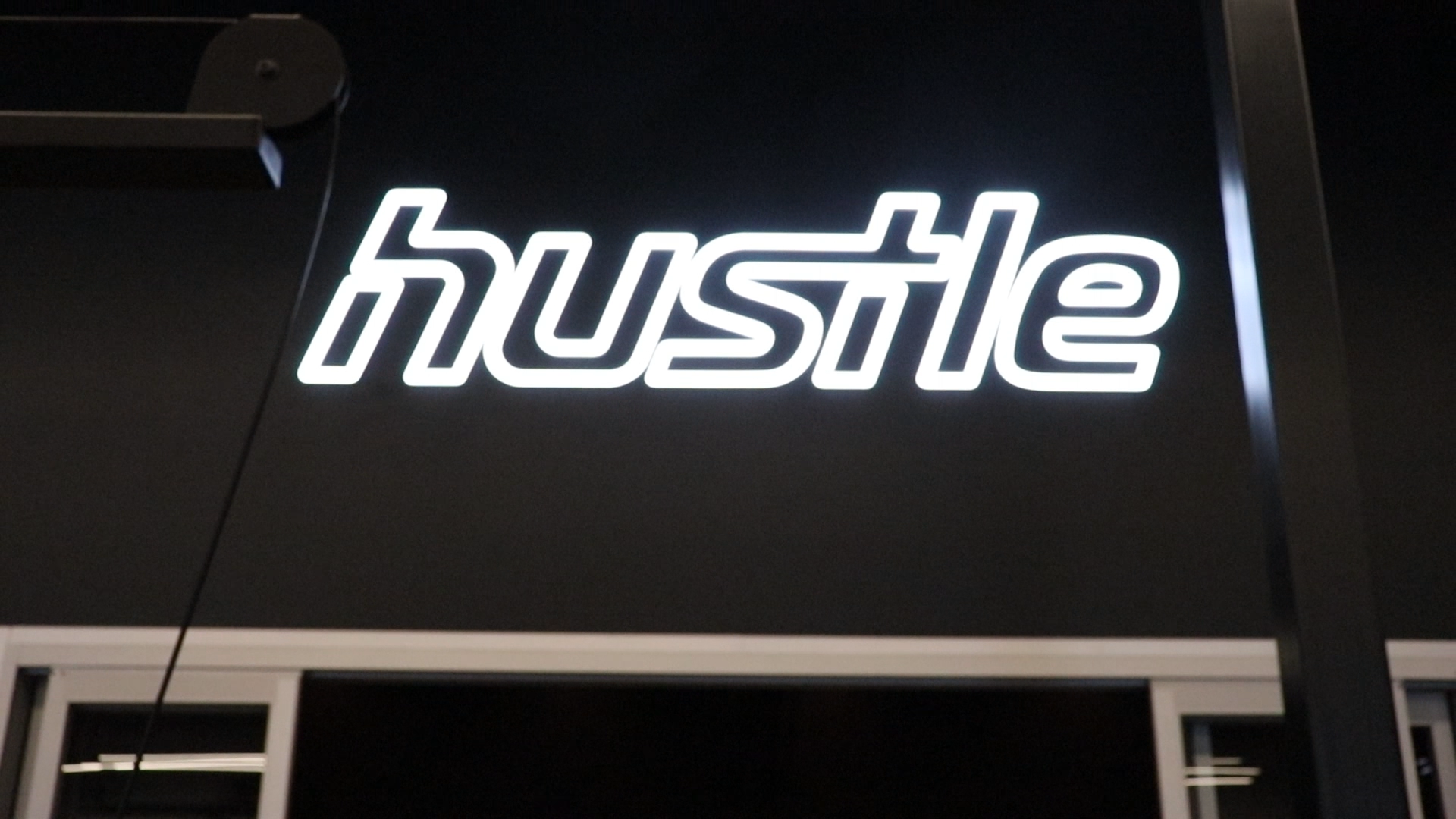 Neon style sign for Hustle, a strength and cardio studio inside Styles Studios, a fitness club in Peoria, IL.