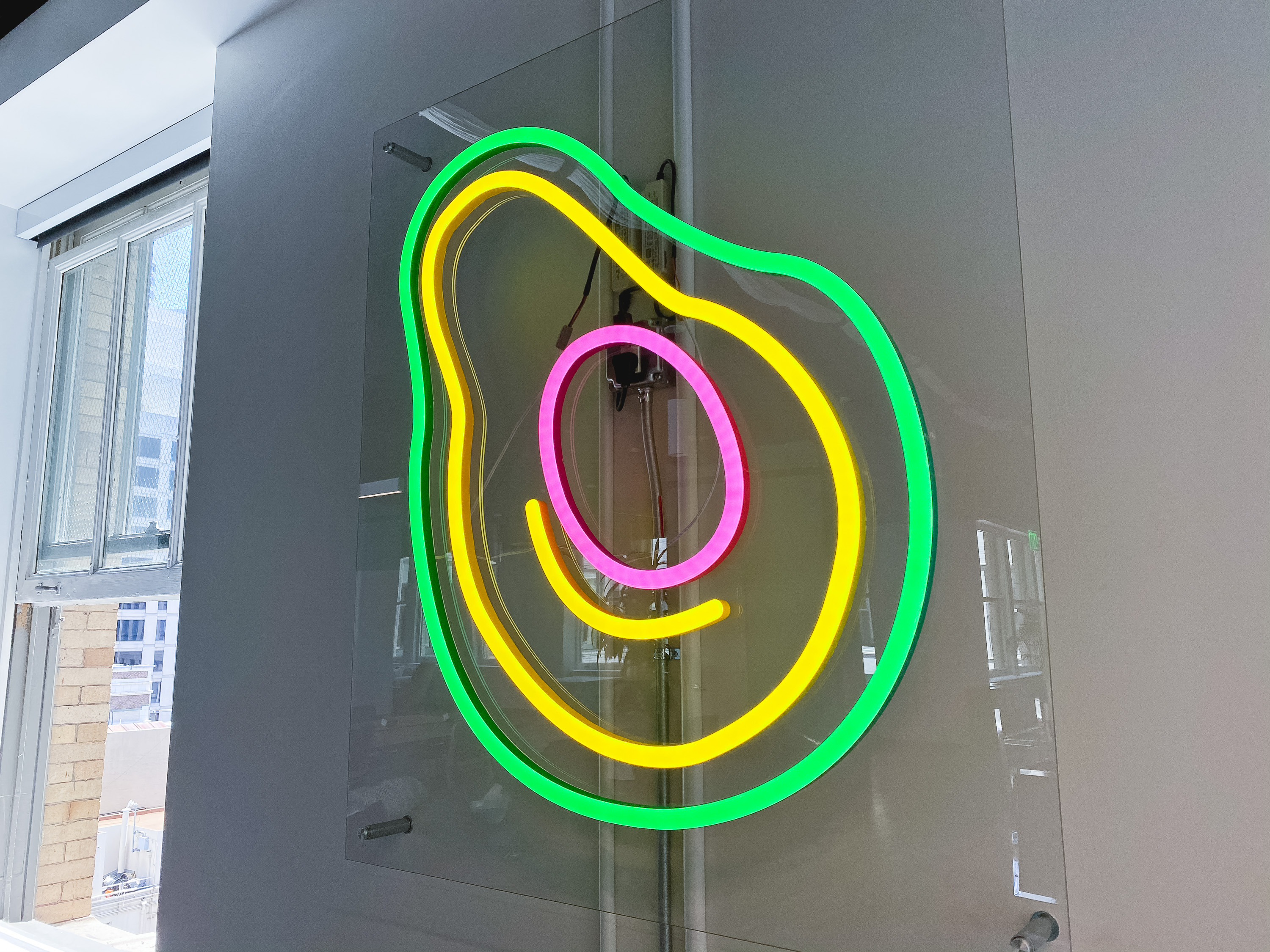 Neon avocado sign with clear acrylic backer on white wall for the San Francisco office of Meltwater, a software as a service company that develops and markets media monitoring and business intelligence software. Neon avocado sign with clear acrylic backer on white wall for the San Francisco office of Meltwater, a software as a service company that develops and markets media monitoring and business intelligence software.