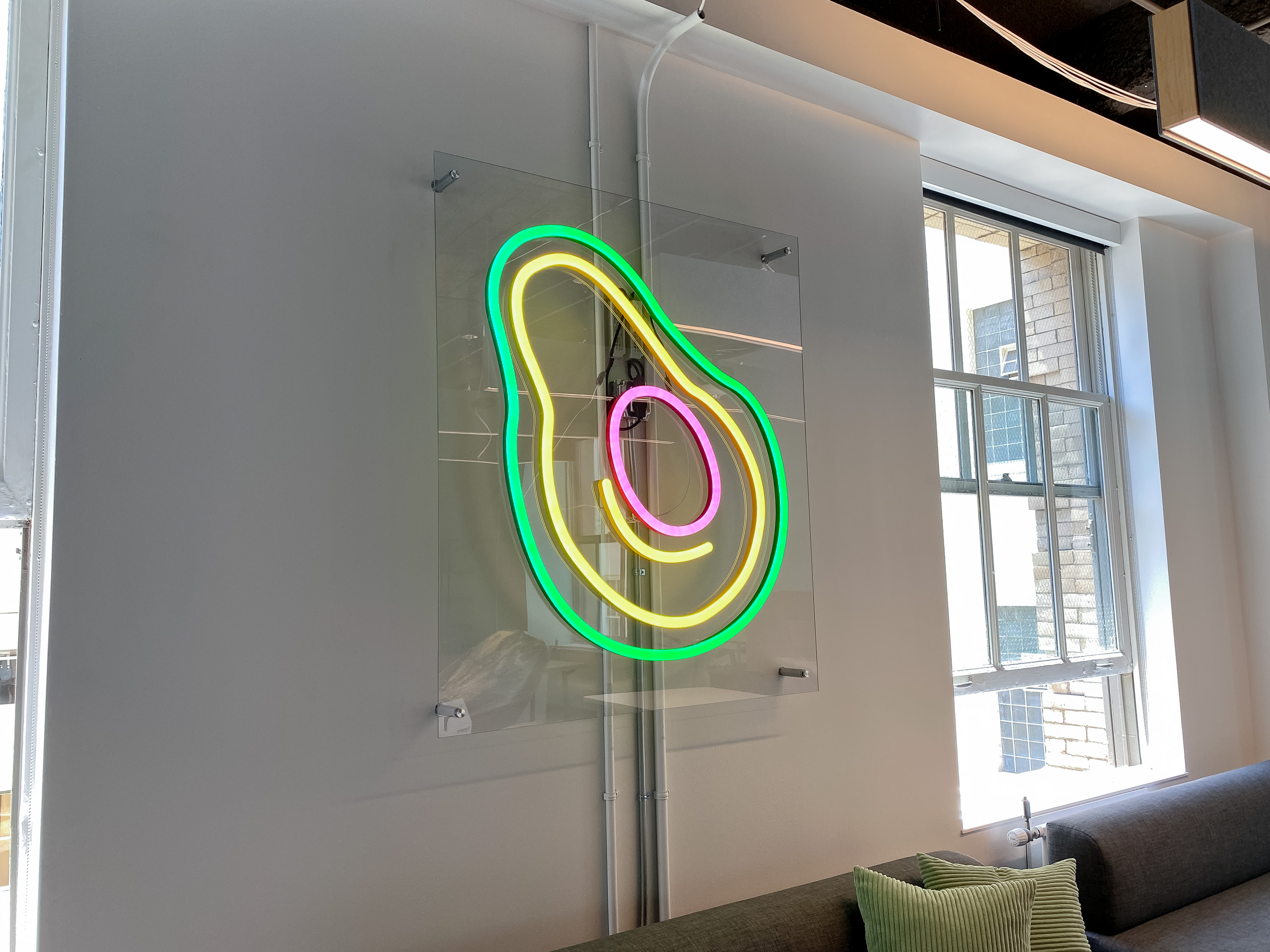 Neon avocado sign with clear acrylic backer on white wall for the San Francisco office of Meltwater, a software as a service company that develops and markets media monitoring and business intelligence software. Neon avocado sign with clear acrylic backer on white wall for the San Francisco office of Meltwater, a software as a service company that develops and markets media monitoring and business intelligence software.