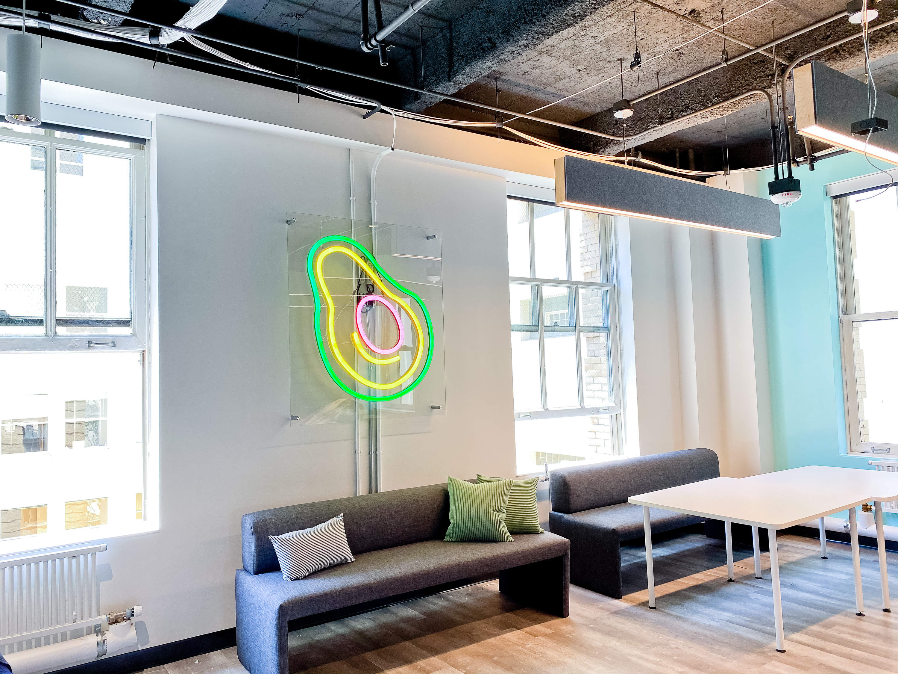 Neon avocado sign with clear acrylic backer on white wall for the San Francisco office of Meltwater, a software as a service company that develops and markets media monitoring and business intelligence software.