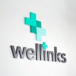 Green and grey lobby/reception logo sign for Wellinks, a wearable health technology company based in New Haven, Connecticut.