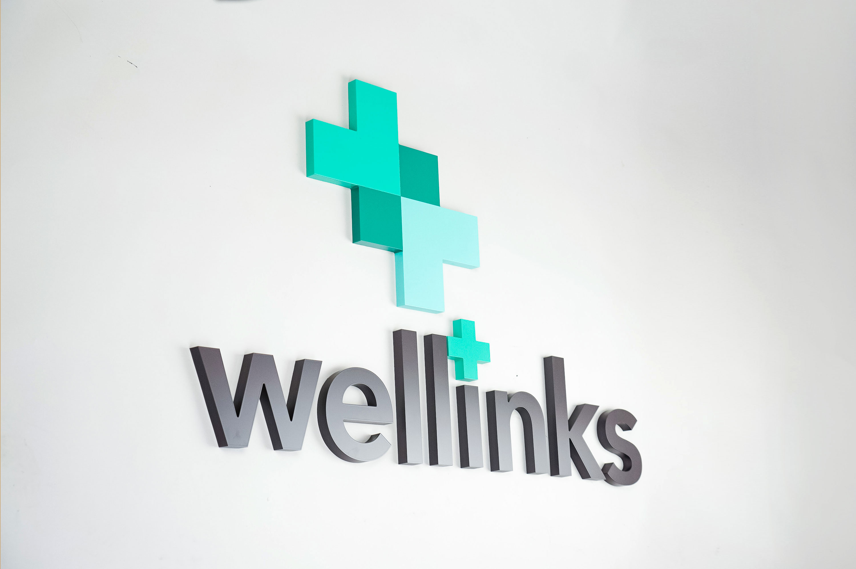 Green and grey lobby/reception logo sign for Wellinks, a wearable health technology company based in New Haven, Connecticut.