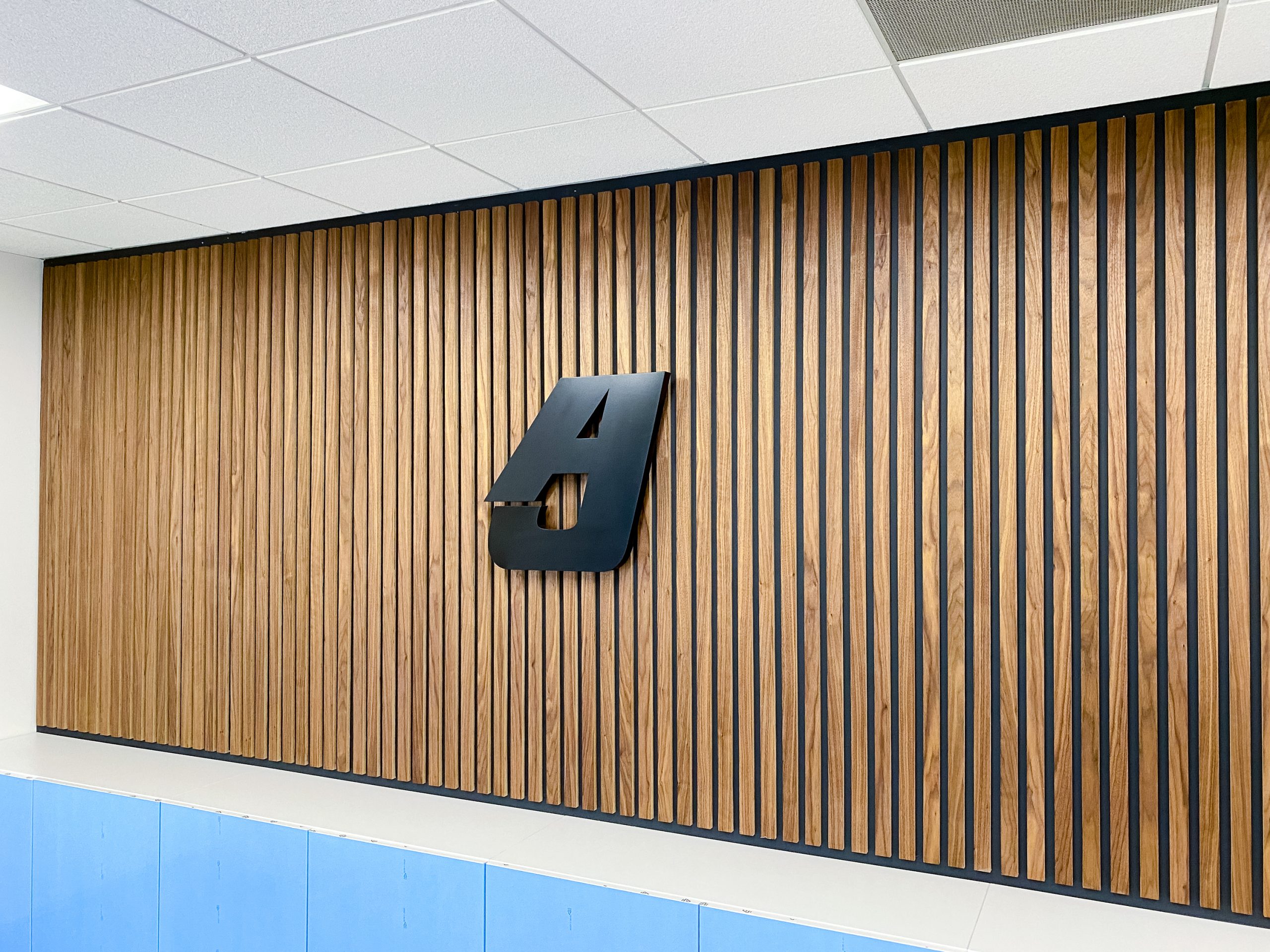 Illuminated, back-lit black sign for slat wood wall for the lobby of Anning-Johnson Company, one of the country’s largest specialty construction companies.