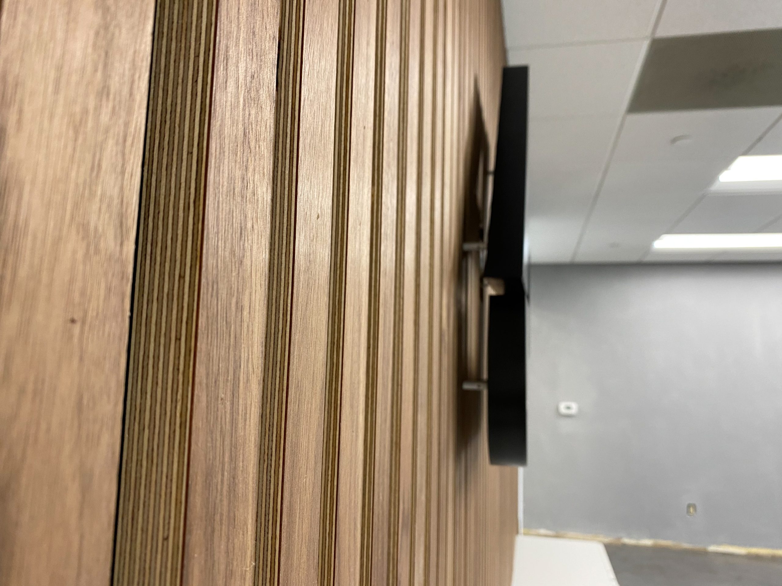 Illuminated, back-lit black sign for slat wood wall for the lobby of Anning-Johnson Company, one of the country’s largest specialty construction companies.