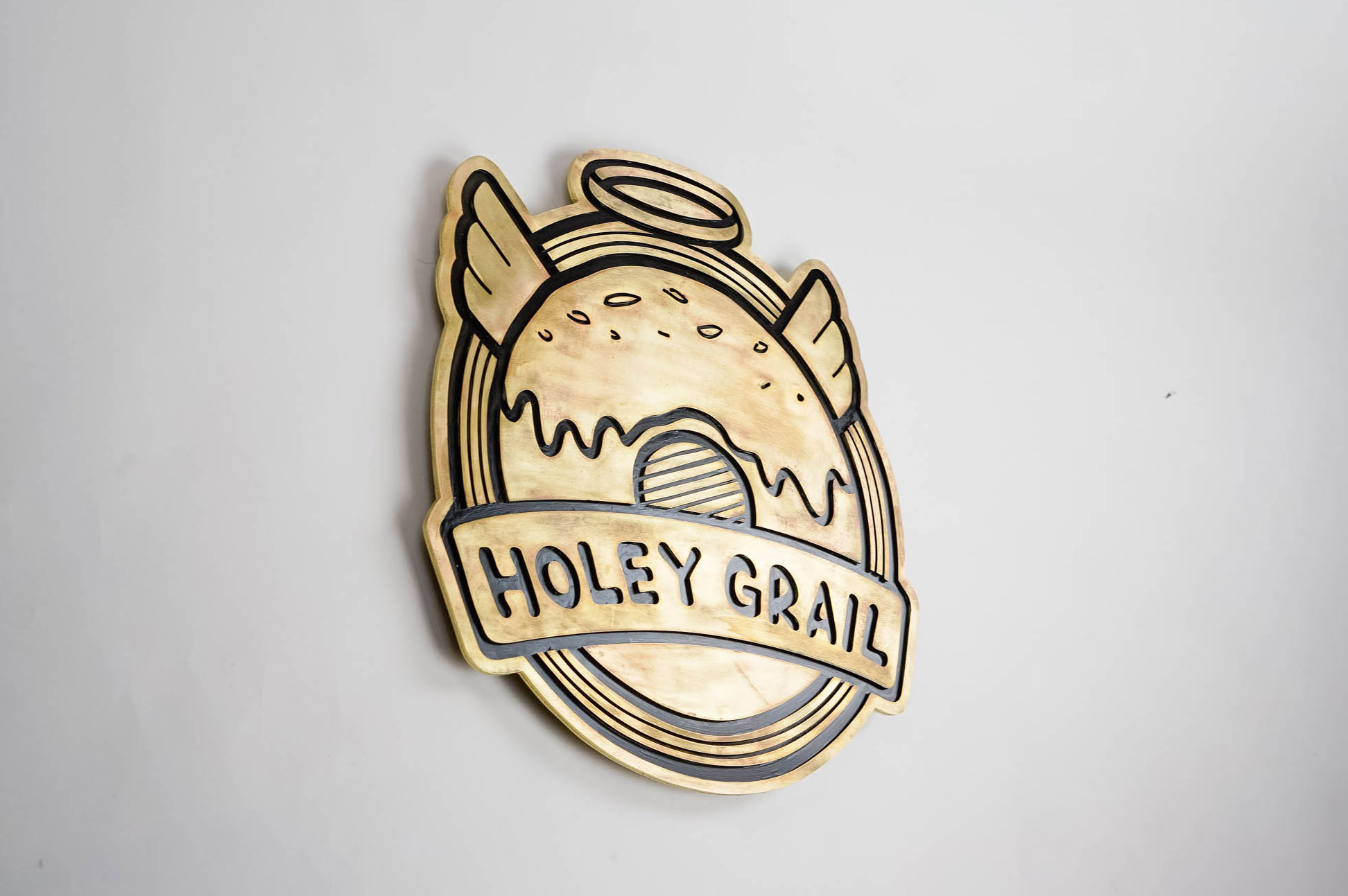 Patinated, retro brass sign for Holey Grail, a donut shop based in Hawaii.