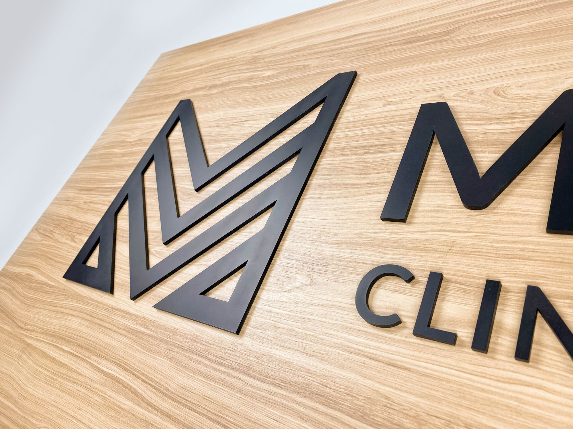 Midtown Clinic of Chiropractic Black logo on light wood laminate panel for the Midtown Clinic of Chiropractic, a full-service chiropractic treatment center serving the Lake Worth, FL area.