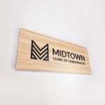Black logo on light wood laminate panel for the Midtown Clinic of Chiropractic, a full-service chiropractic treatment center serving the Lake Worth, FL area.