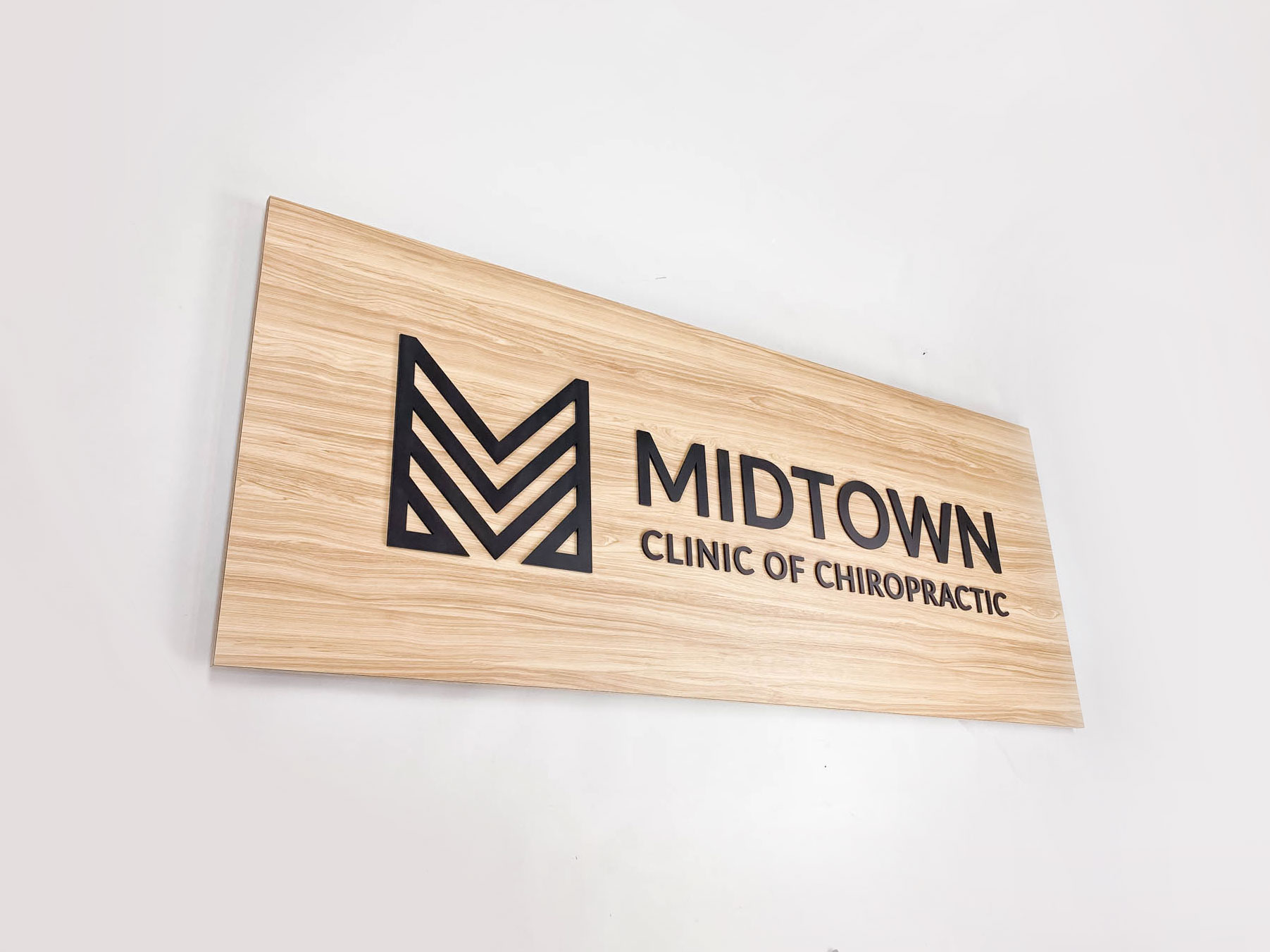 Midtown Clinic of Chiropractic Black logo on light wood laminate panel for the Midtown Clinic of Chiropractic, a full-service chiropractic treatment center serving the Lake Worth, FL area.
