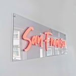 Pink script LED neon sign on clear backer for the San Francisco office of Meltwater, a software as a service company that develops and markets media monitoring and business intelligence software.