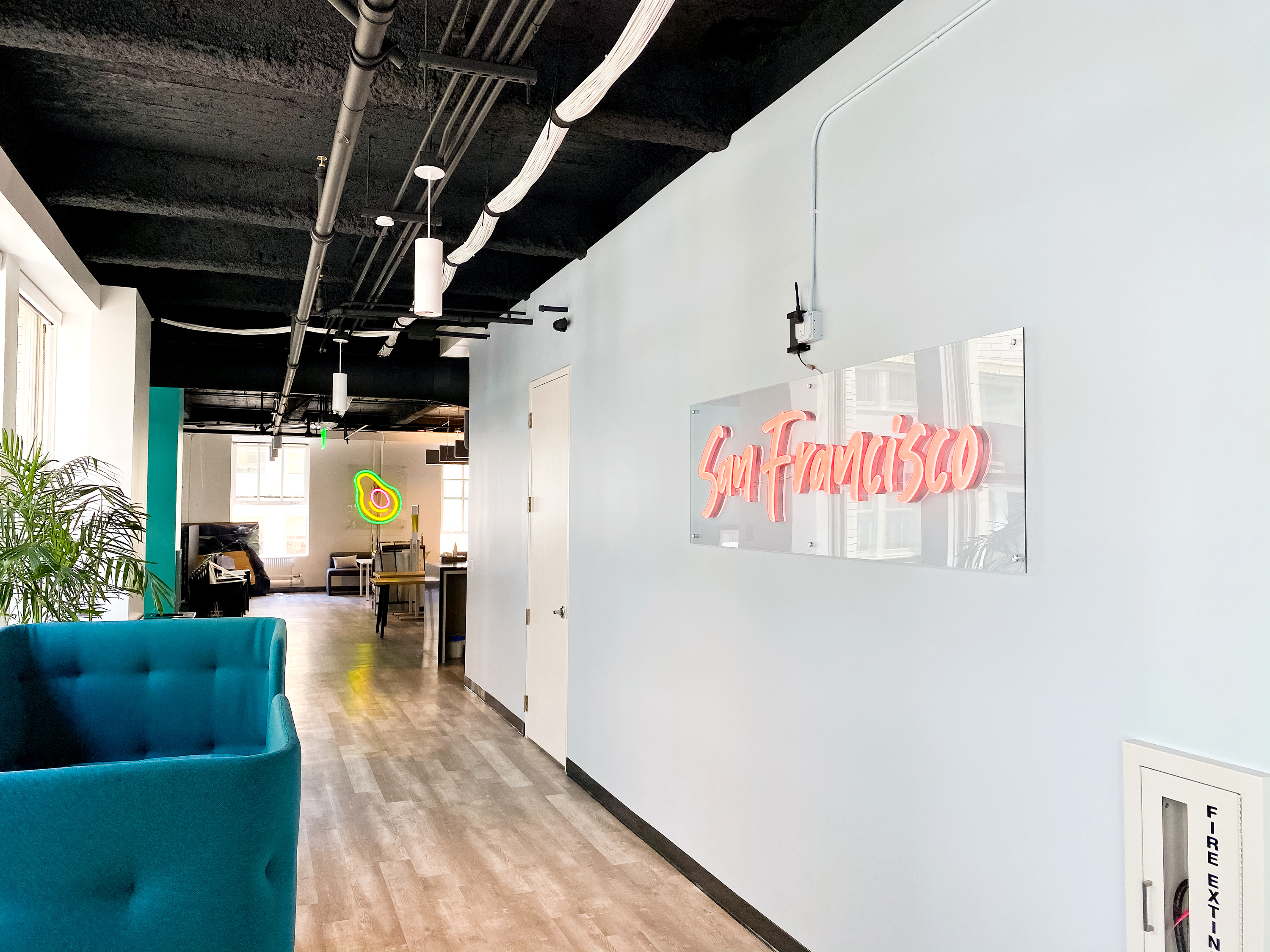 Pink script LED neon sign on clear backer for the San Francisco office of Meltwater, a software as a service company that develops and markets media monitoring and business intelligence software.