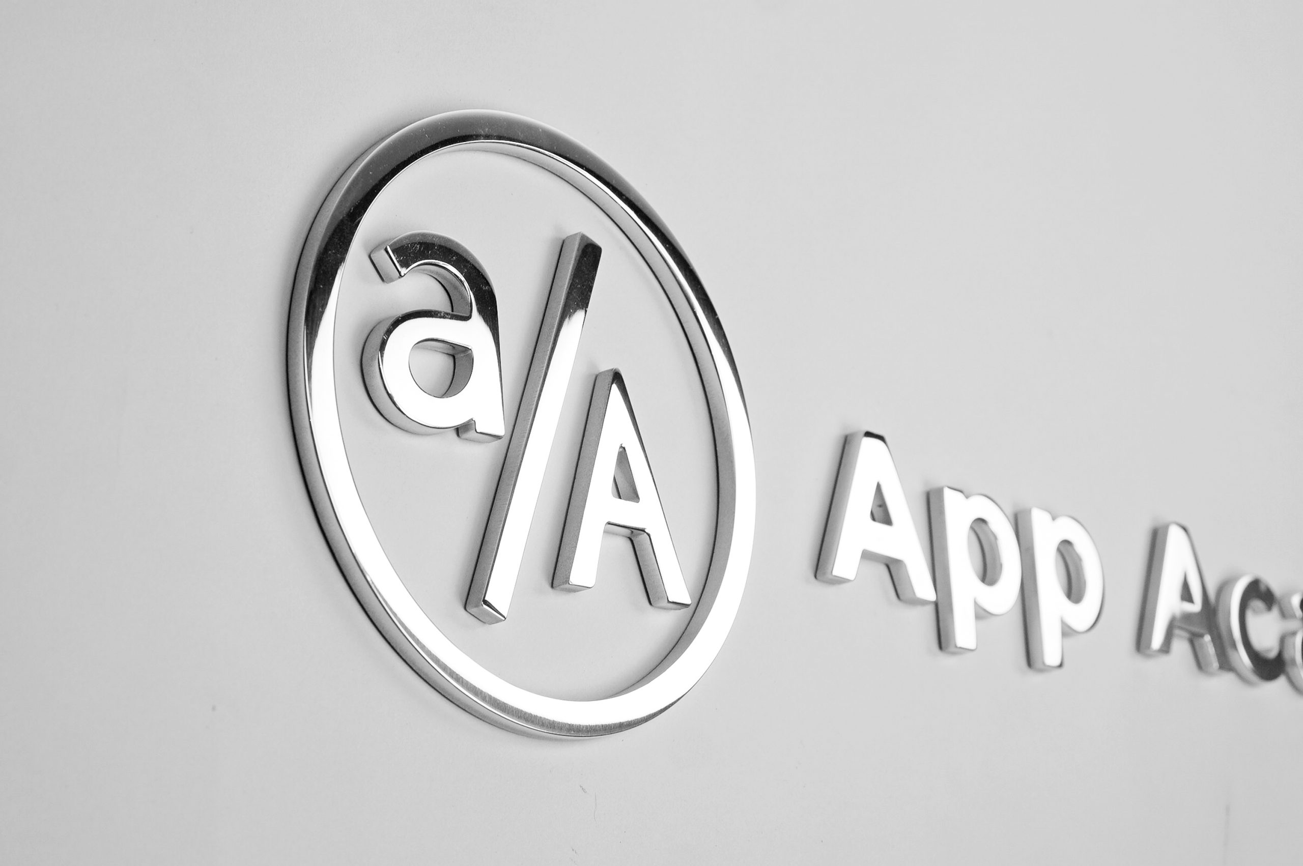 Polished metal sign for granite column for the New York office of App Academy, a software training institute.