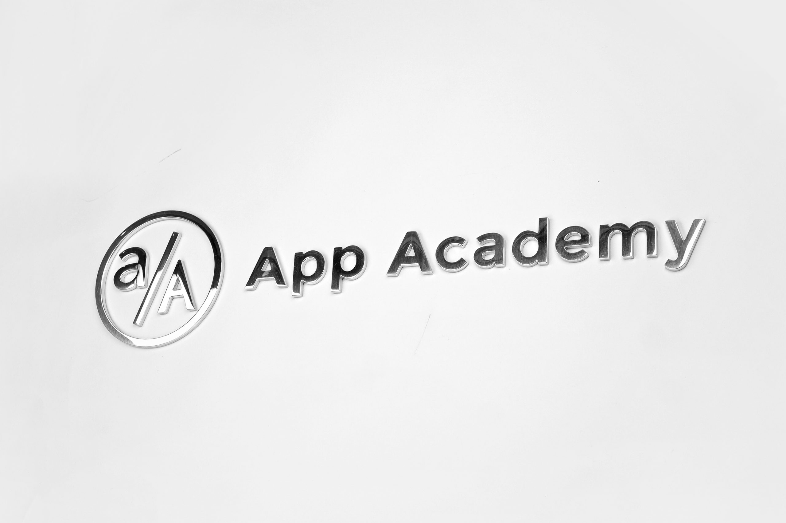 Polished metal sign for granite column for the New York office of App Academy, a software training institute.