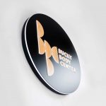 Illuminated, black and light wood edge-lit sign on moss wall for the Bucky Body Center, a body plastic and reconstructive surgery center in Philadelphia, PA.