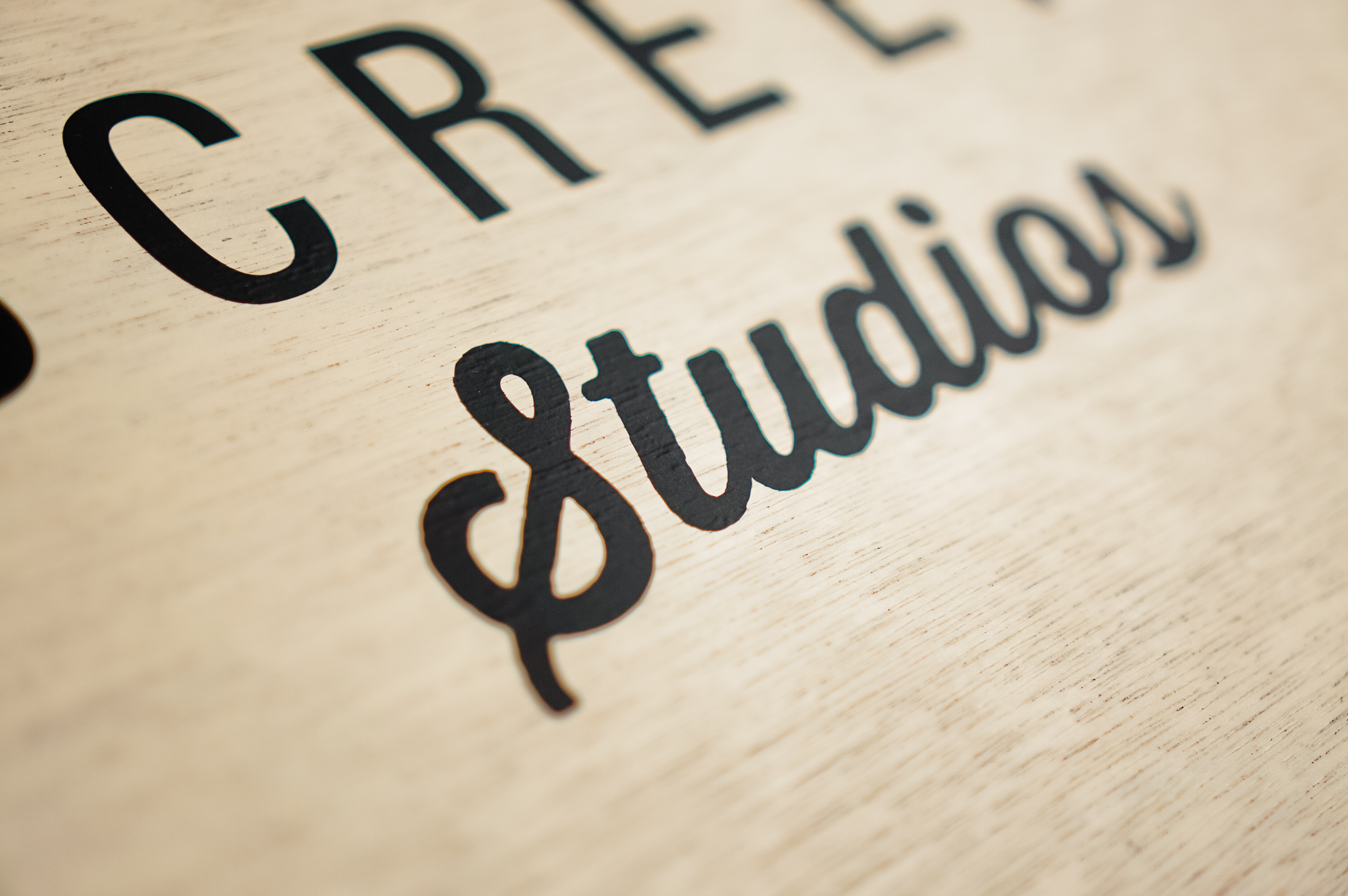 Wood hanging blade sign with black artwork for the storefront of Small Screen Studios, a shop in Cleveland, OH.