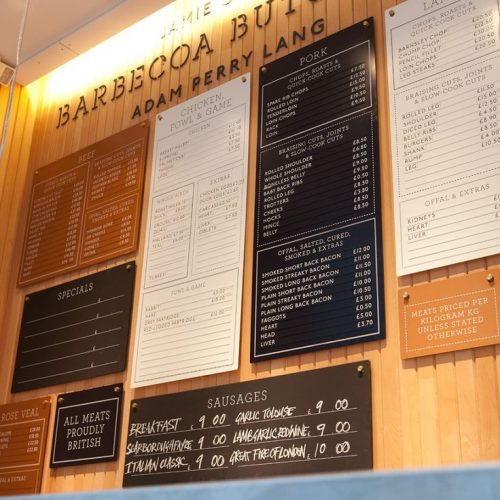 Menu display on wood wall with magnetic letters at Jamie Oliver's Barbecoa Butchery.