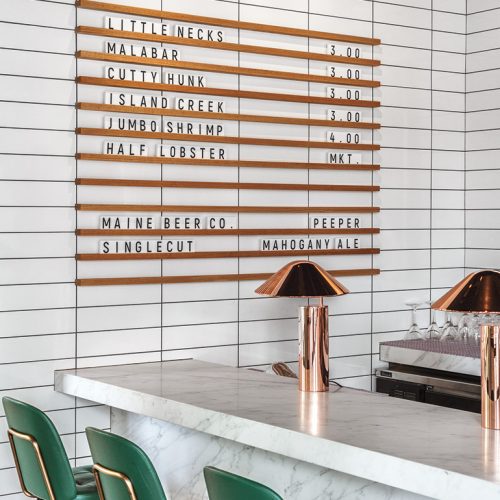 Letterboard letters in wood rails on tile wall at Glass House, a bar and restaurant in Cambridge, MA. Designed by
Hacin + Associates.