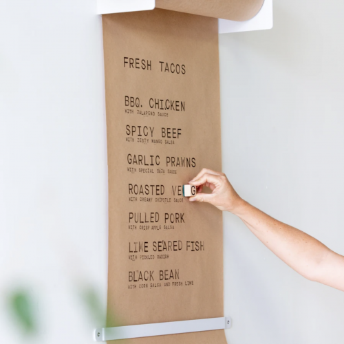 Person stamping letters on butcher paper menu using menu kit by George and WIlly