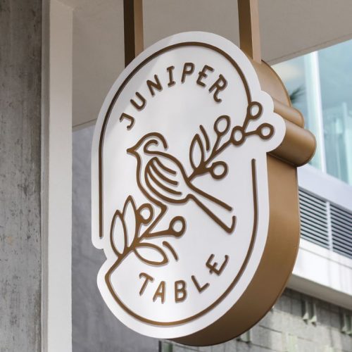 Modern bronze and white overhead sign for Juniper Table, a Mediterranean restaurant and cafe in Palm Springs, CA.
