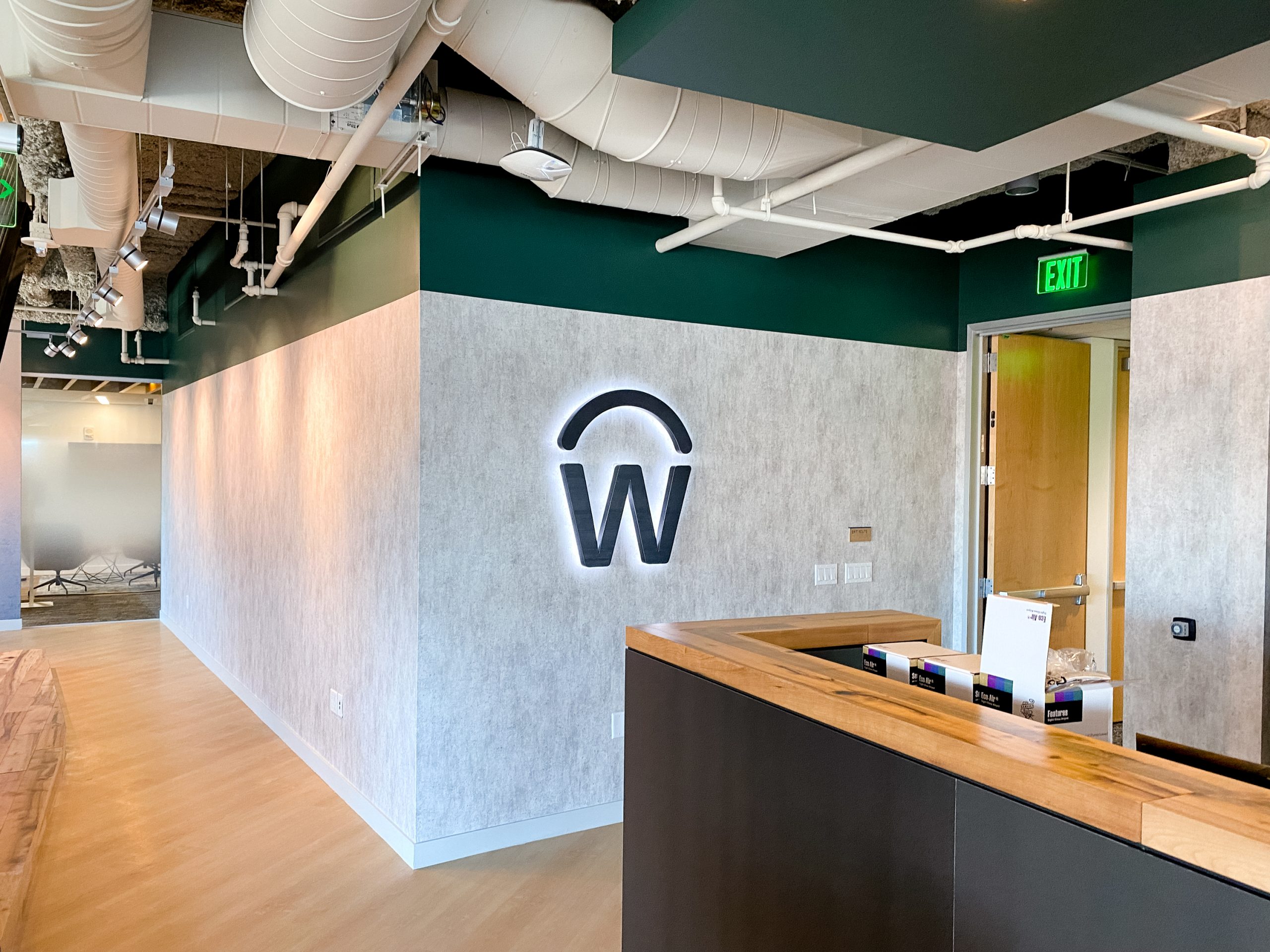 Illuminated, backlit, aged metal sign on concrete lobby wall for the San Francisco office of Workday, a software company.