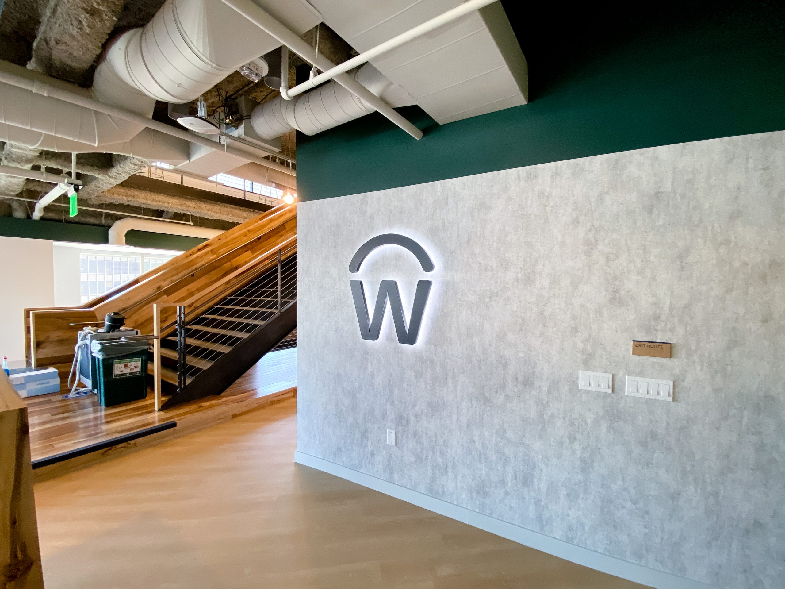 Illuminated, backlit, aged metal sign on concrete lobby wall for the San Francisco office of Workday, a software company.