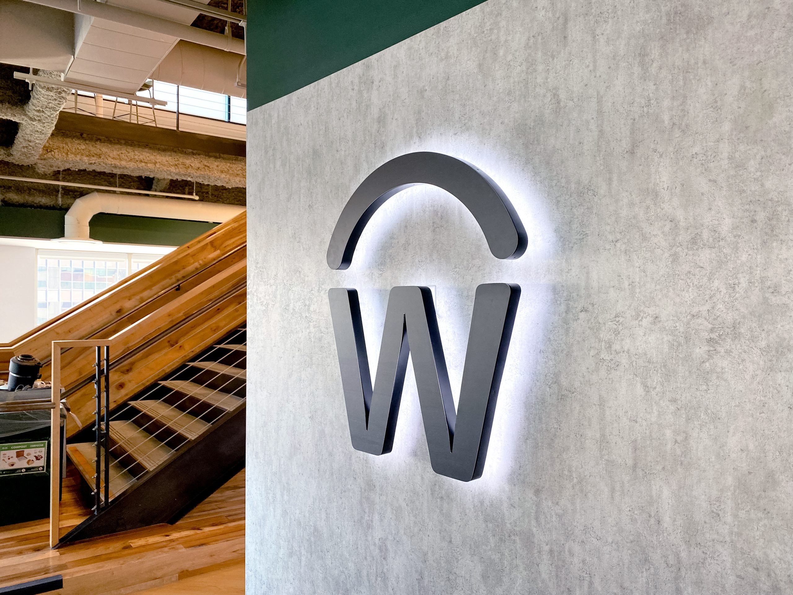 Illuminated, backlit, aged metal sign on concrete lobby wall for the San Francisco office of Workday, a software company.