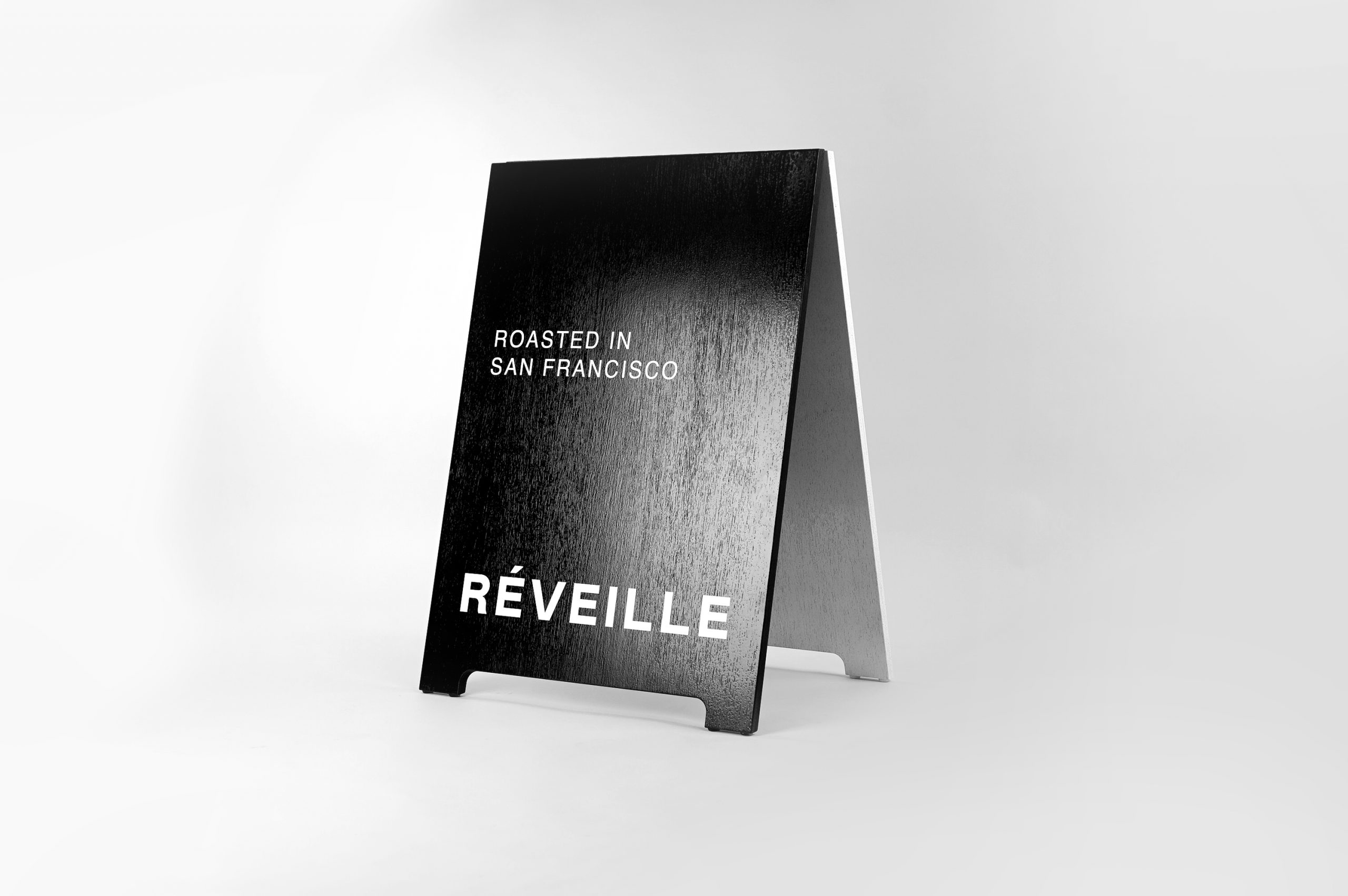 Black and white painted A-frame sign with alternating colors for Cafe Réveille, a San Francisco based specialty coffee roaster and coffee shop chain.